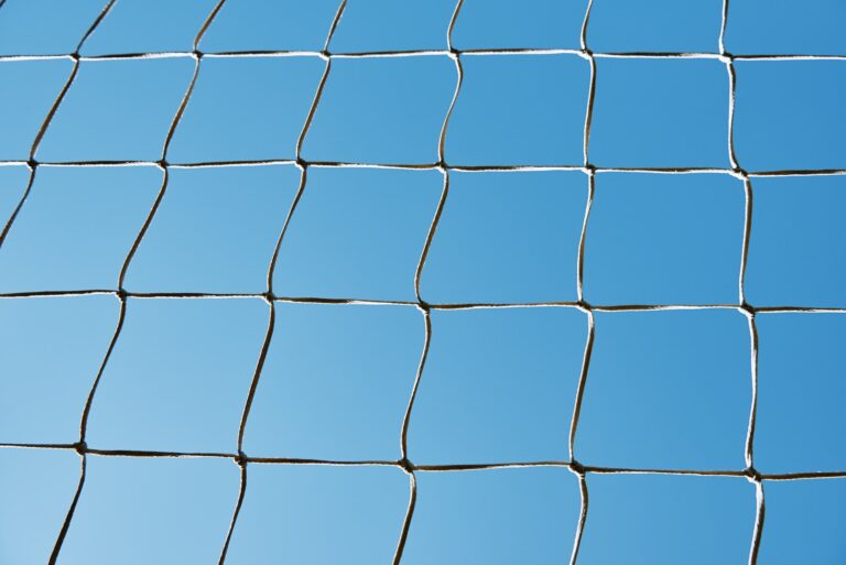 Soccer or football cage texture against blue sky