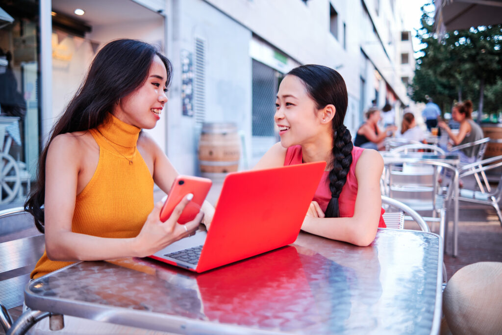 two asian women using a computer outdoor